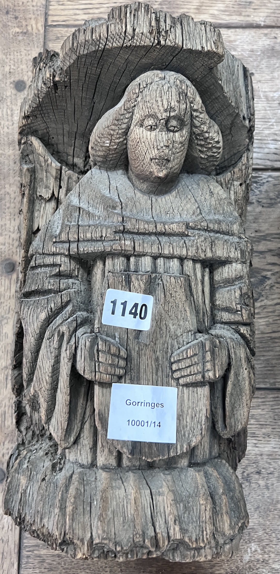 A late 16th carved pine misericord, modelled as a bishop holding a plaque, height 36cm